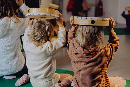 Drei kleine Kinder mit einer Trommel auf dem Kopf