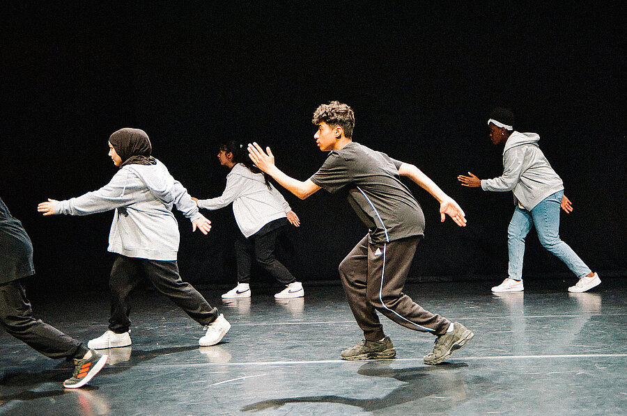 Mehrere Jugendliche tanzen auf einer Bühne.